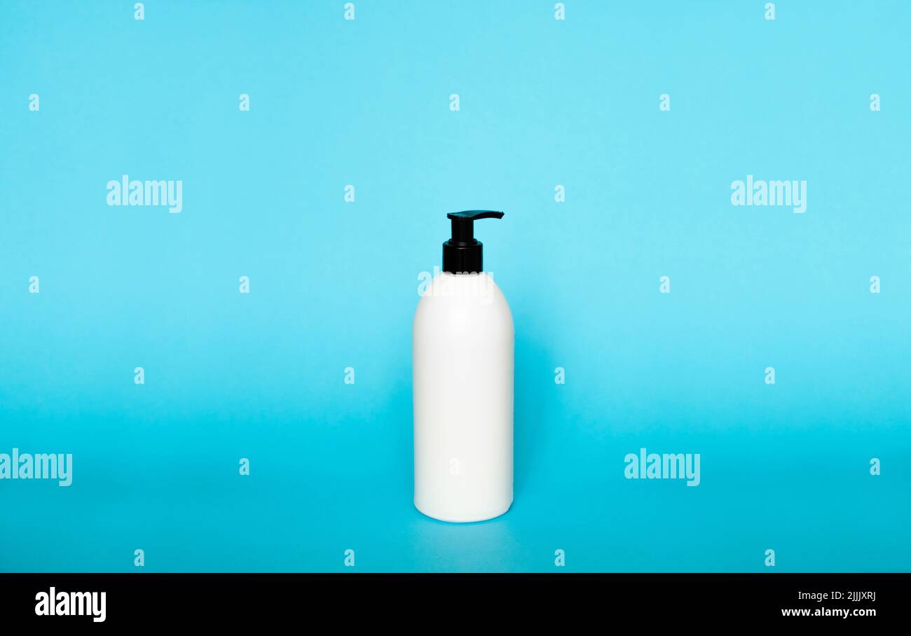 Flacon distributeur de savon en plastique blanc isolé sur fond bleu. Lotion pour le soin de la peau. Produit essentiel pour le bain. Bouteille de shampooing. Bain et corps Banque D'Images