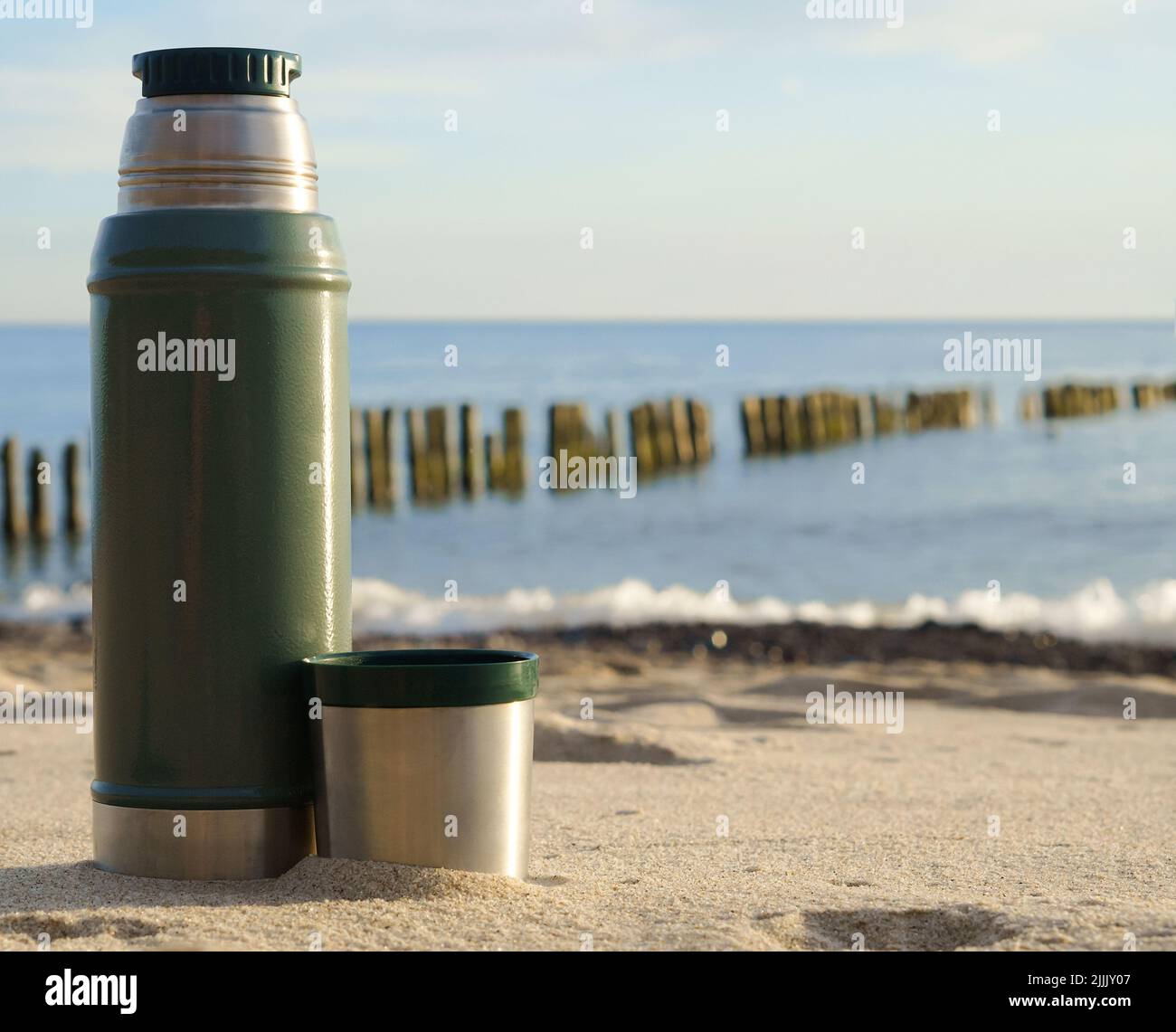 Boire du thé sur la mer. Thermos avec thé sur le fond de la nature. Banque D'Images