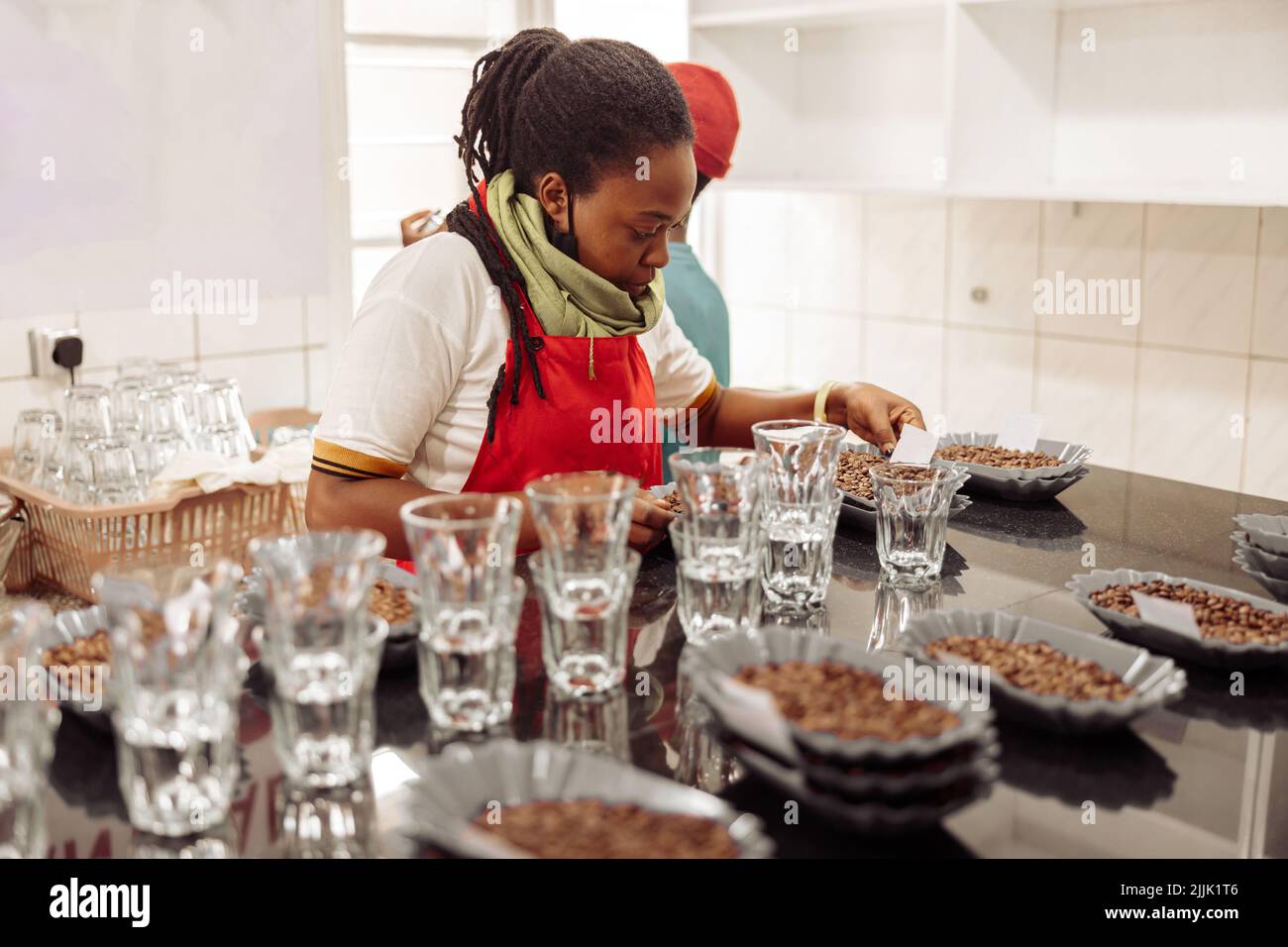 Une dame afro-américaine pose des notes sur des assiettes avec du café pour la dégustation Banque D'Images