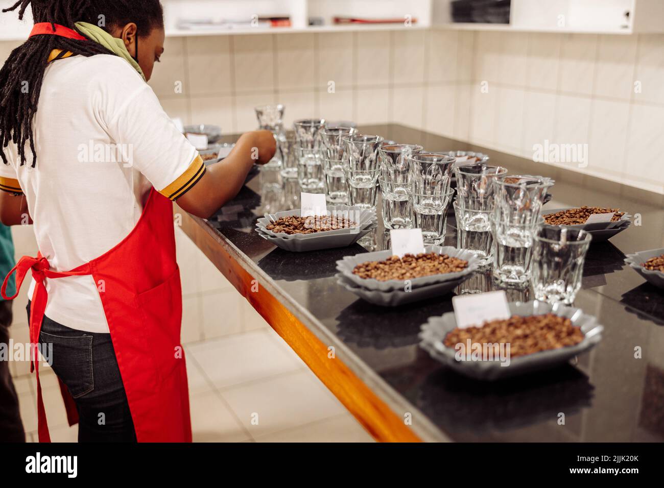 Femme afro-américaine mettant des notes sur des assiettes avec du café pour la dégustation Banque D'Images