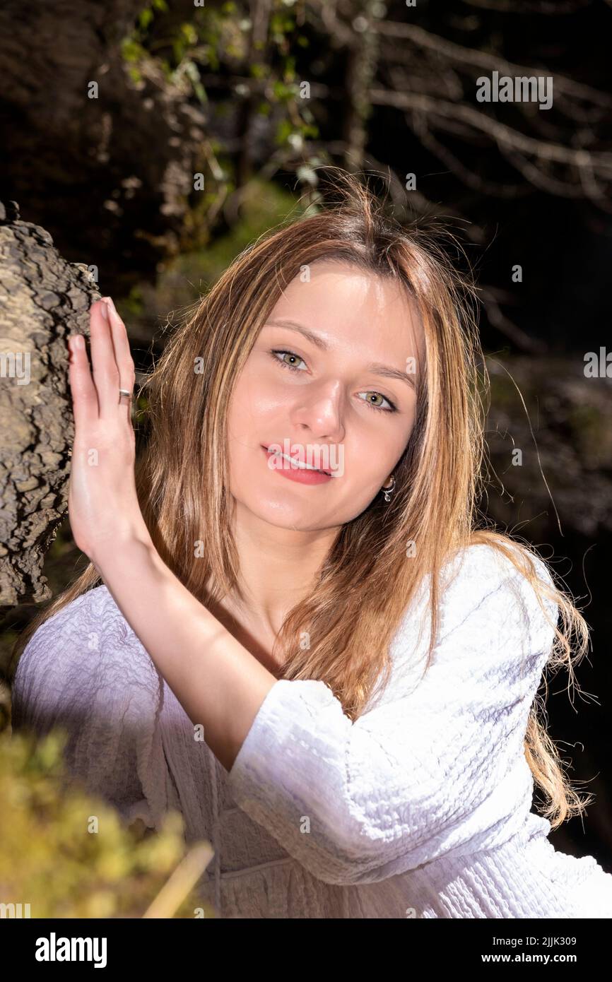 femme blonde dans une robe blanche assise dans la forêt Banque D'Images