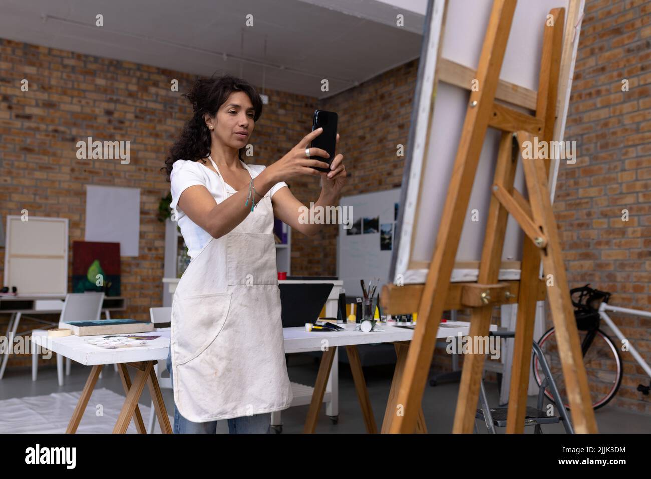 Image d'une artiste biraciale prenant une photo de nouveau tableau en studio Banque D'Images