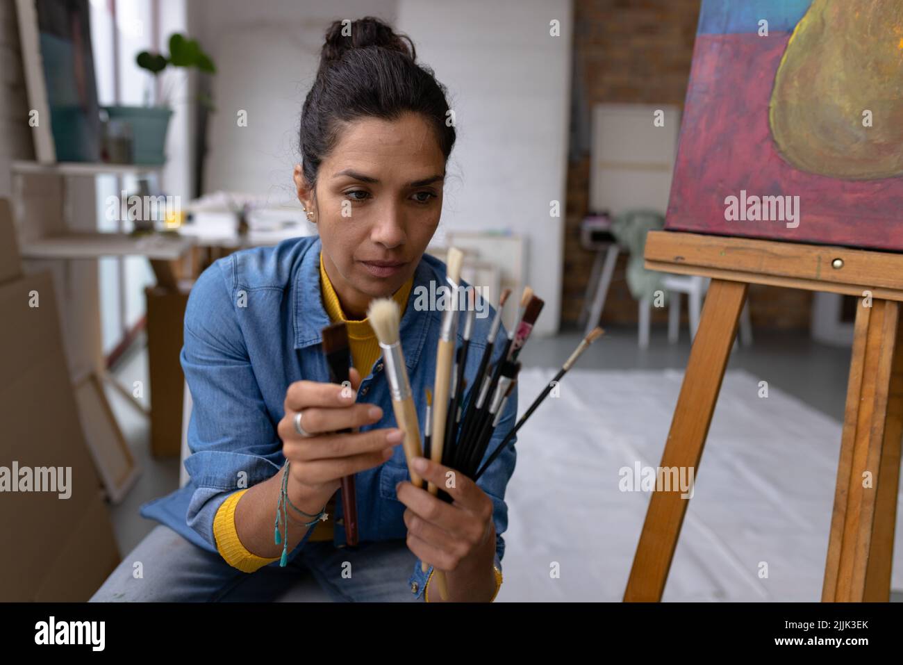 Image d'une artiste biraciale avec pinceaux en studio Banque D'Images