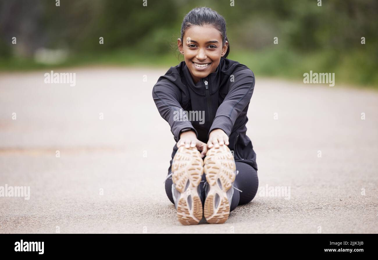 Les courses tôt le matin ne sont que sa chose. Portrait d'une jeune femme sportive qui étire les jambes tout en faisant de l'exercice à l'extérieur. Banque D'Images