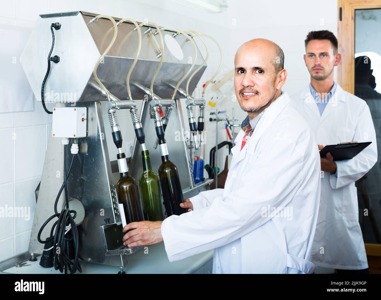 portrait d'un travailleur de cave de vinification avec des machines d'embouteillage en usine Banque D'Images