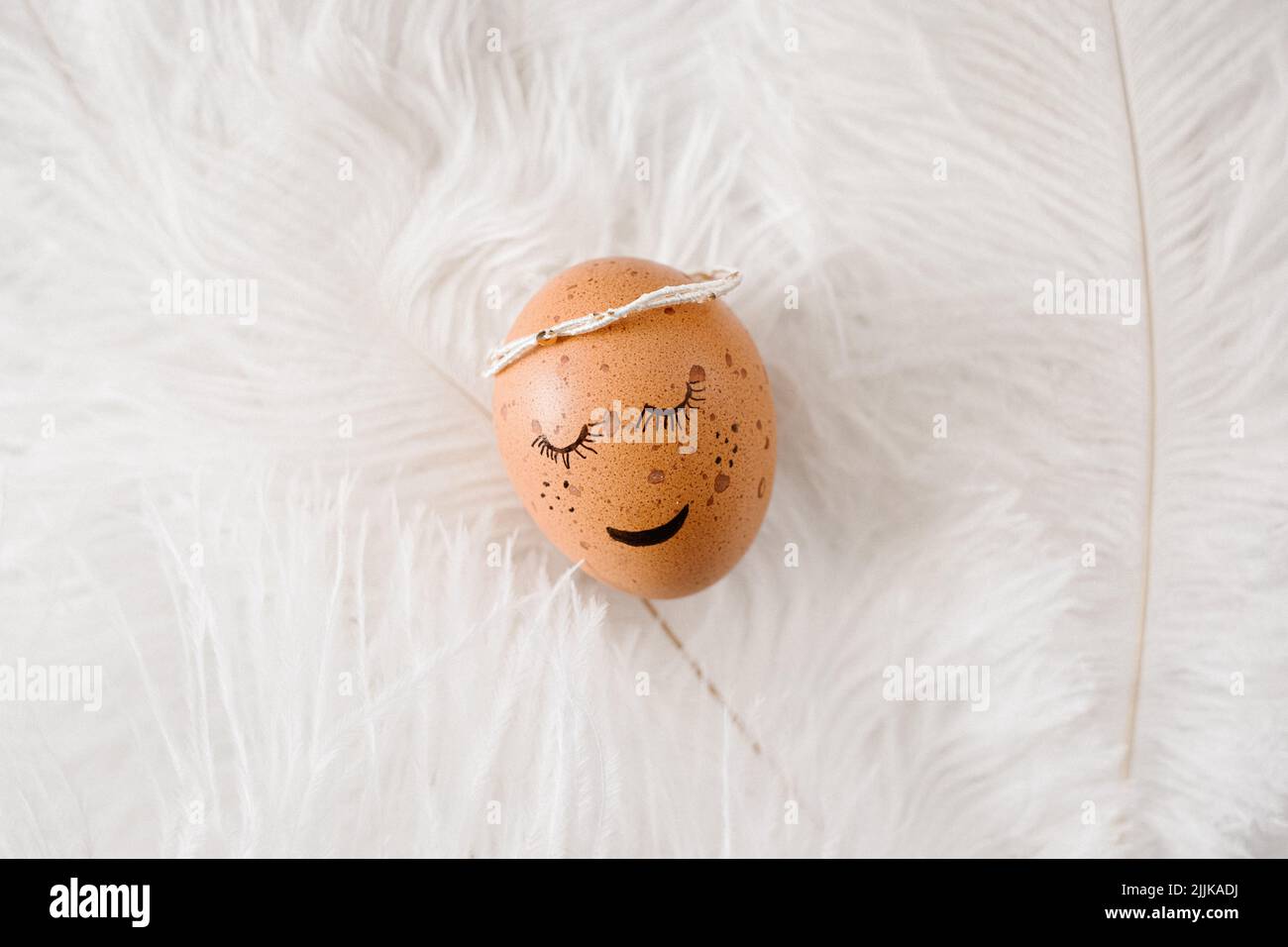 Gros plan d'un œuf avec un visage dessiné sur des plumes blanches. Banque D'Images