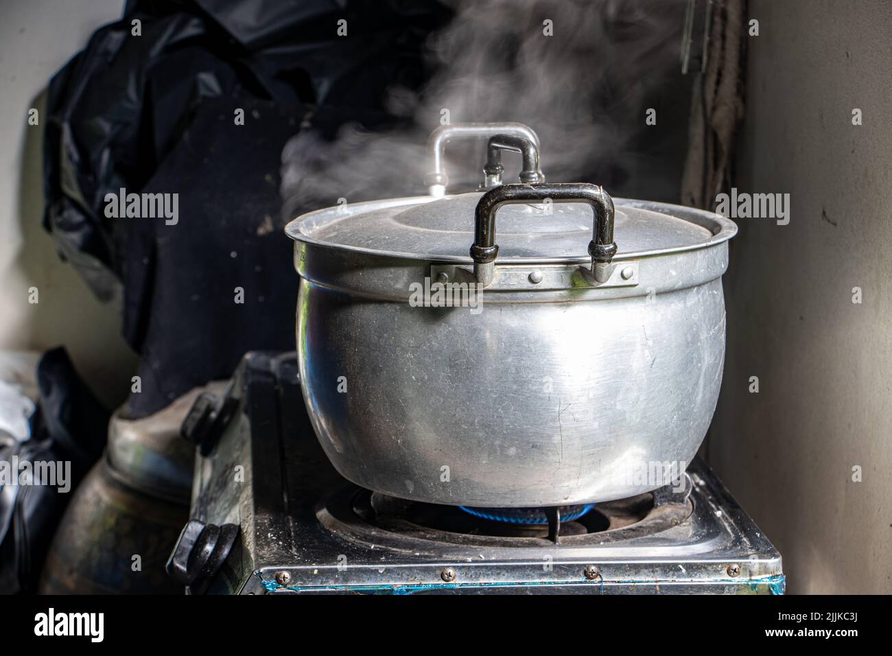 La vapeur s'élève de la casserole en aluminium sur la cuisinière Banque D'Images