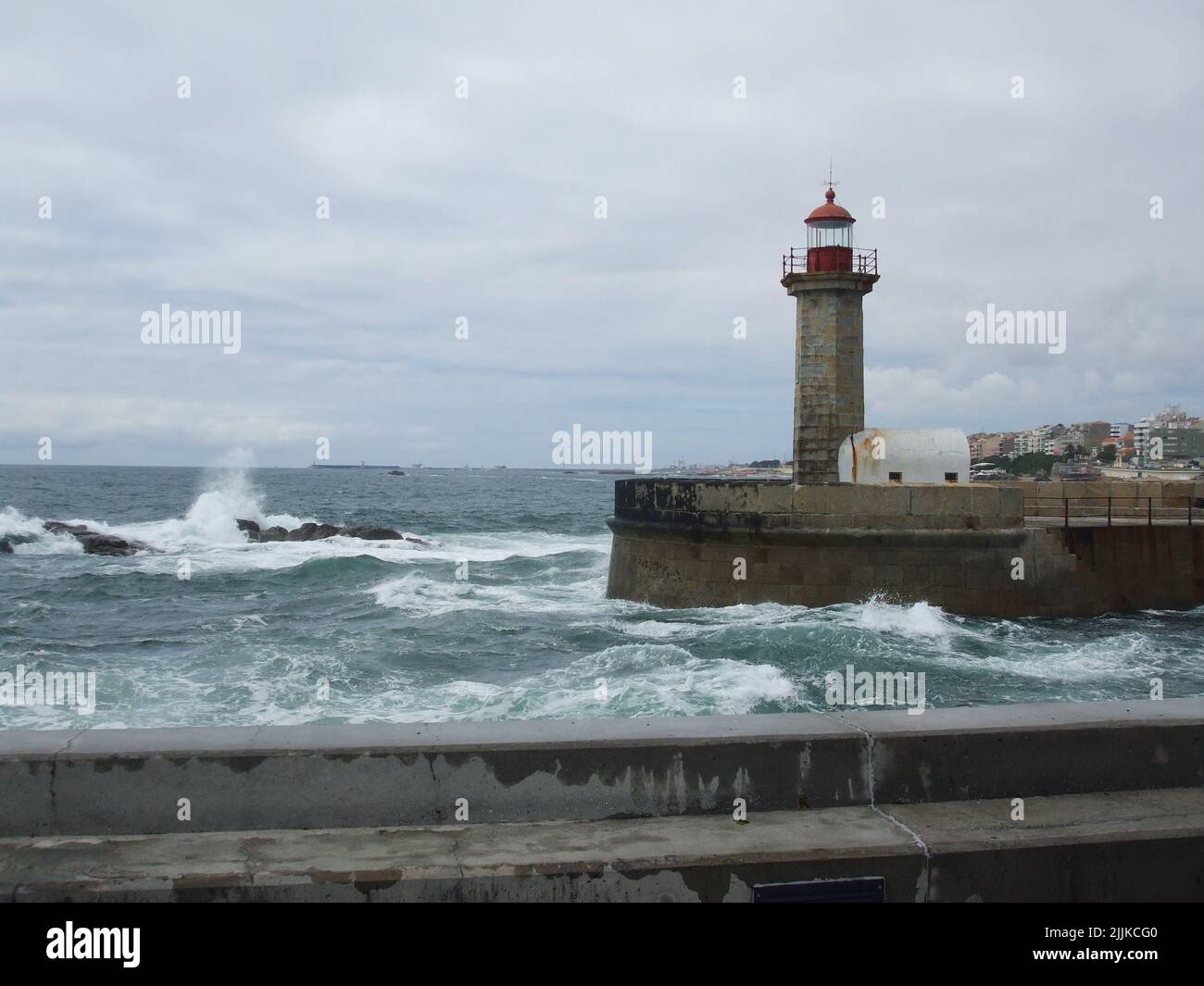 Phare Foz do Douro à côté d'un plan d'eau et d'un ciel nuageux et clair en arrière-plan Banque D'Images