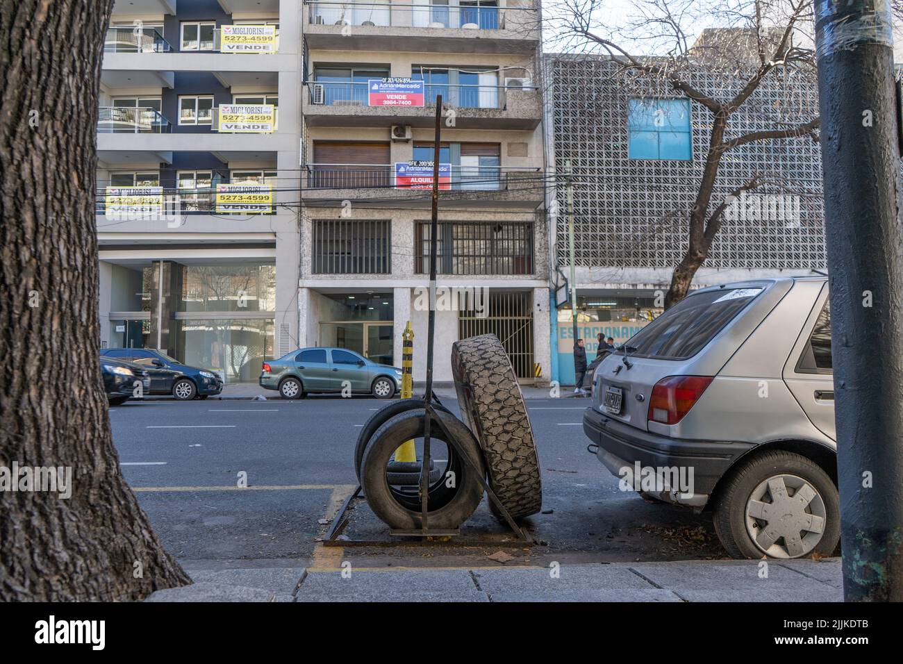 Photo générale d'une rue, où nous voyons des roues de voiture, derrière une voiture grise garée Banque D'Images