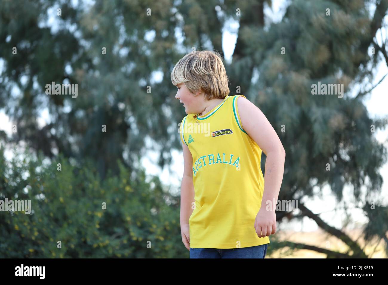 Un garçon portant un maillot de basket-ball australien sur le fond d'un arbre Banque D'Images