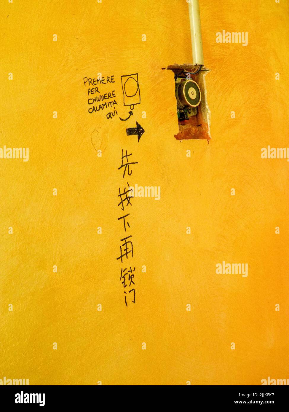 Un cliché vertical d'un script chinois sur le mur jaune près d'un interrupteur à Milan, en Italie Banque D'Images