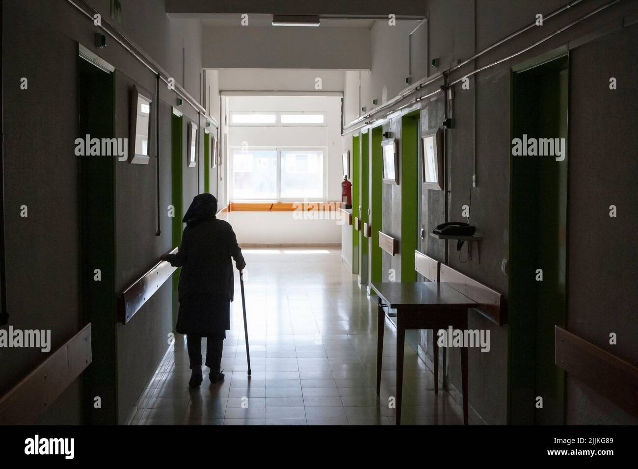 Une femme âgée marchant dans un couloir d'hôpital avec une canne Banque D'Images