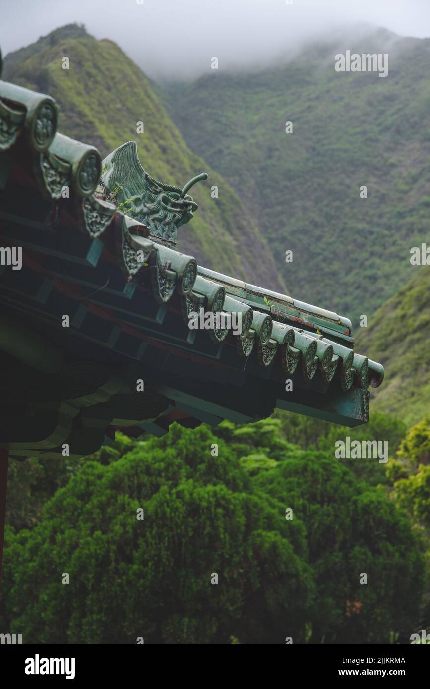 Une belle photo d'un toit traditionnel du temple d'Hawaï avec des montagnes vertes et fumées Banque D'Images