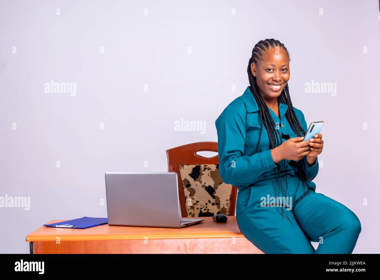 Une femme d'affaires africaine assise à sa table de bureau et utilisant le téléphone Banque D'Images