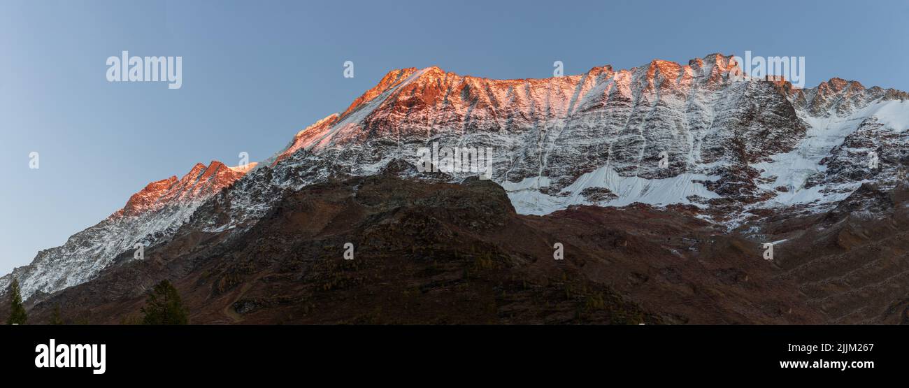 Vue panoramique sur le coucher de soleil orange Alpglow sur la chaîne de montagnes enneigées du Valais loetschental suisse. Lonzahoerner, Breitthorn et Breitlauwihorn. Banque D'Images