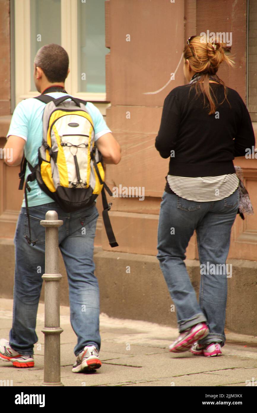 Vue verticale arrière de deux adultes marchant sur le trottoir Banque D'Images