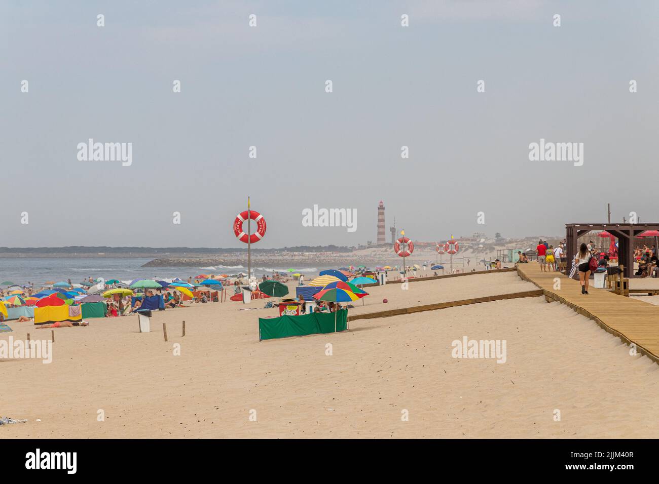 Costa Nova do Prado, Portugal. La célèbre plage de sable blanc donne sur l'océan Atlantique. Avec le phare d'Aveiro en arrière-plan Banque D'Images