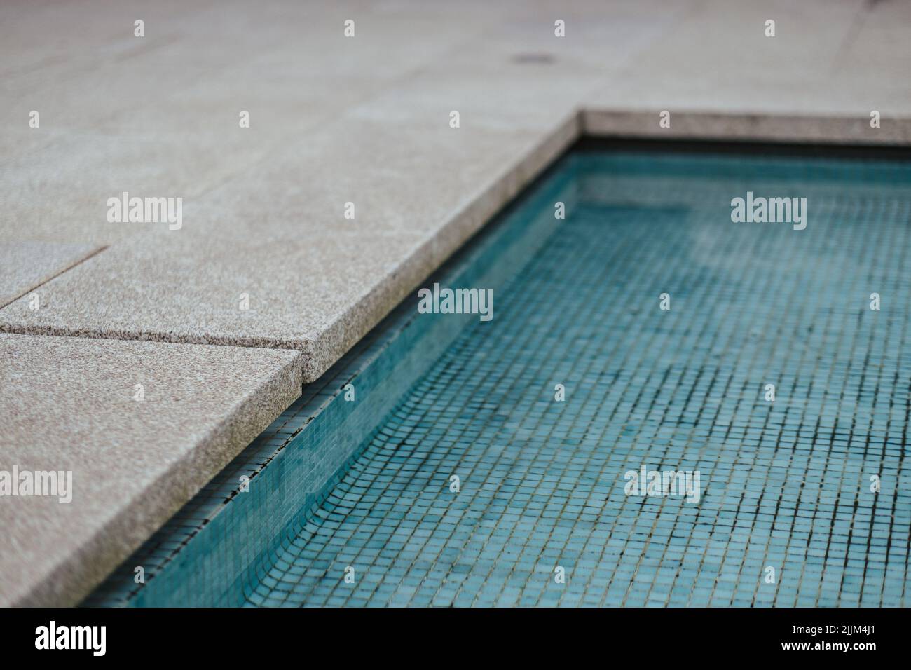 Une piscine intérieure en mosaïque bleue près des côtés en pierre Banque D'Images