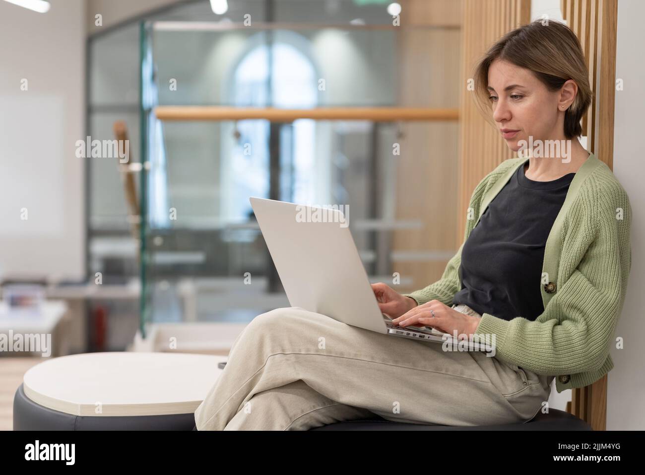 Femme d'âge moyen et pensive travaillant sur un ordinateur portable dans une bibliothèque Banque D'Images