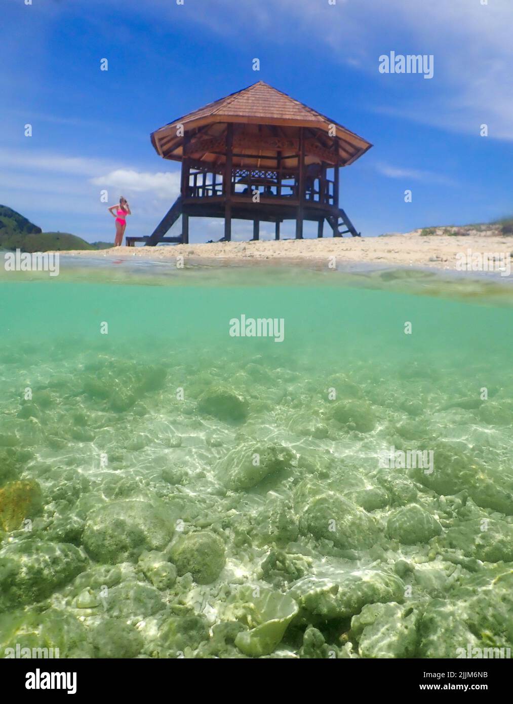 Un cliché vertical d'une femme se tenant sur la plage à côté d'une structure dans un ciel nuageux Banque D'Images
