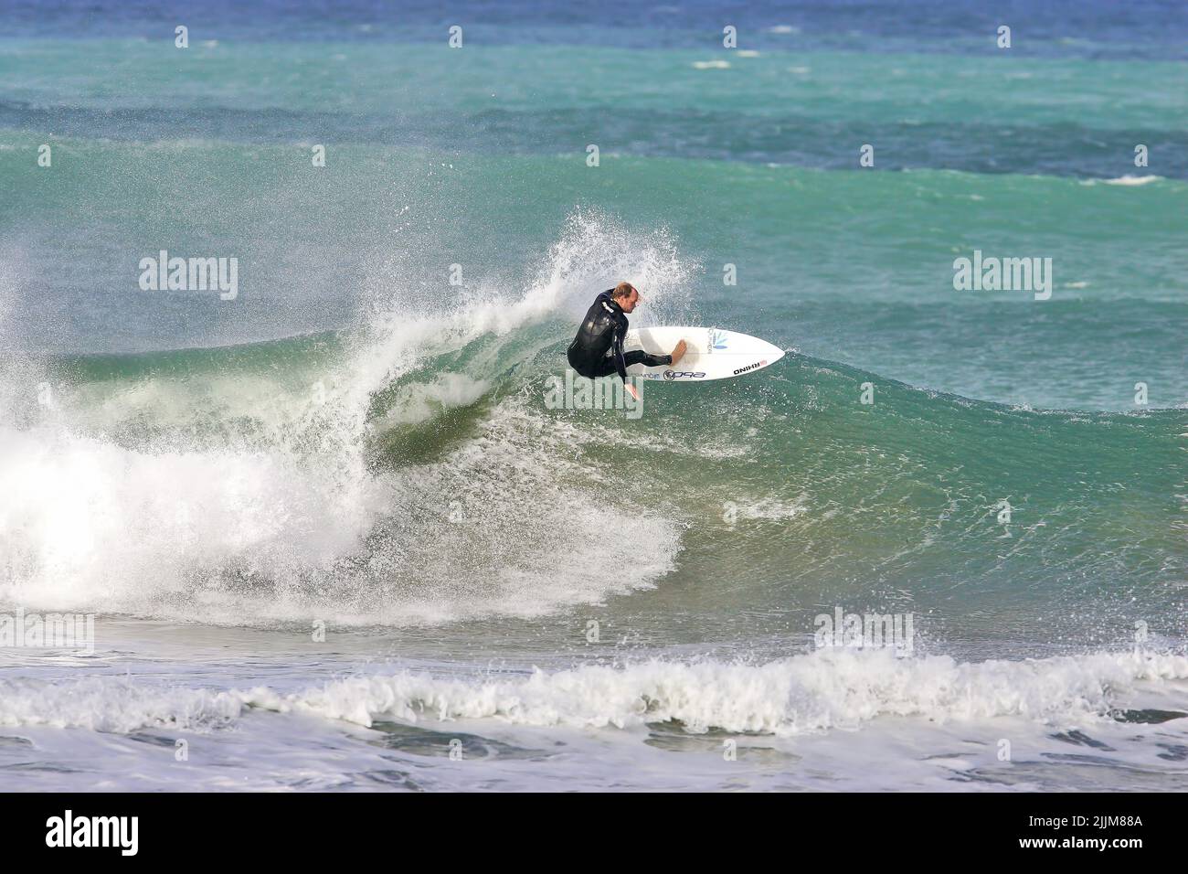 Un surfeur effectuant un tour de haut sur une vague à Fistral Beach Banque D'Images