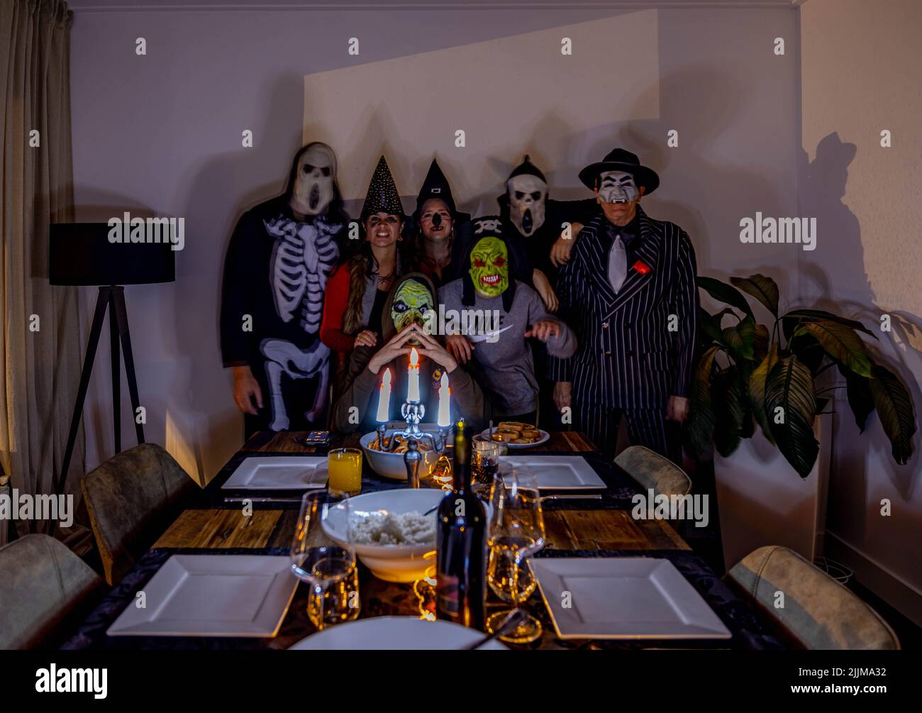 Une famille et des amis célébrant Halloween dans une pièce sombre Banque D'Images