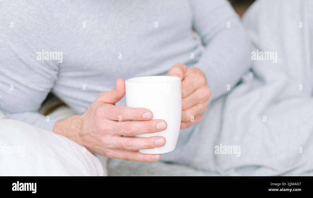 thé du matin boisson homme lit tenir tasse Banque D'Images