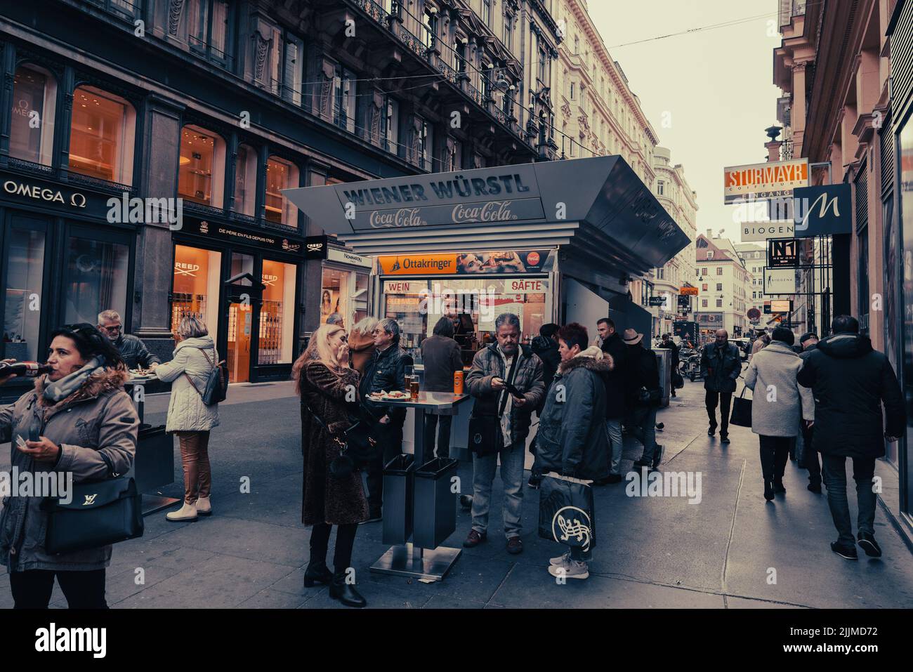 Les gens en face d'un stand de saucisse sur la rue entre de beaux vieux bâtiments à Vienne, Autriche Banque D'Images