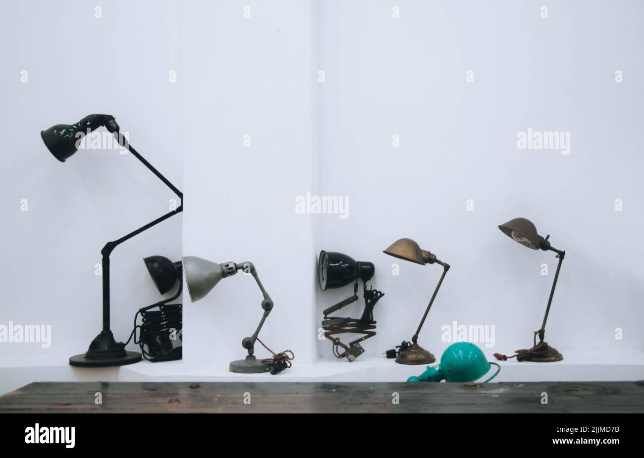 Une rangée de différentes lampes sur une table isolée sur un fond de mur blanc Banque D'Images