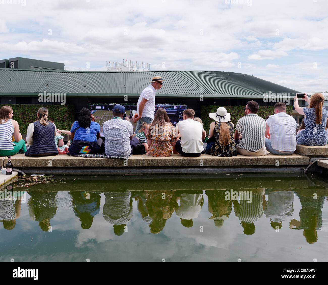 Championnat de tennis de Wimbledon. Les spectateurs assis sur le bord d'un étang à la colline devant le premier terrain. Londres Banque D'Images