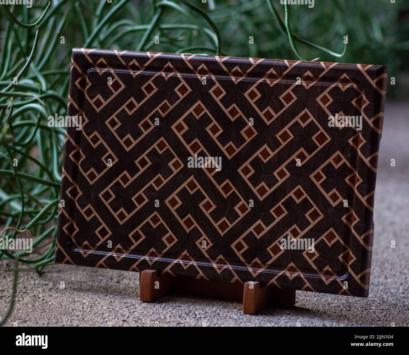 Une planche à découper en bois de fin de grain fabriquée à la main en noyer, érable et acajou sur un support Banque D'Images