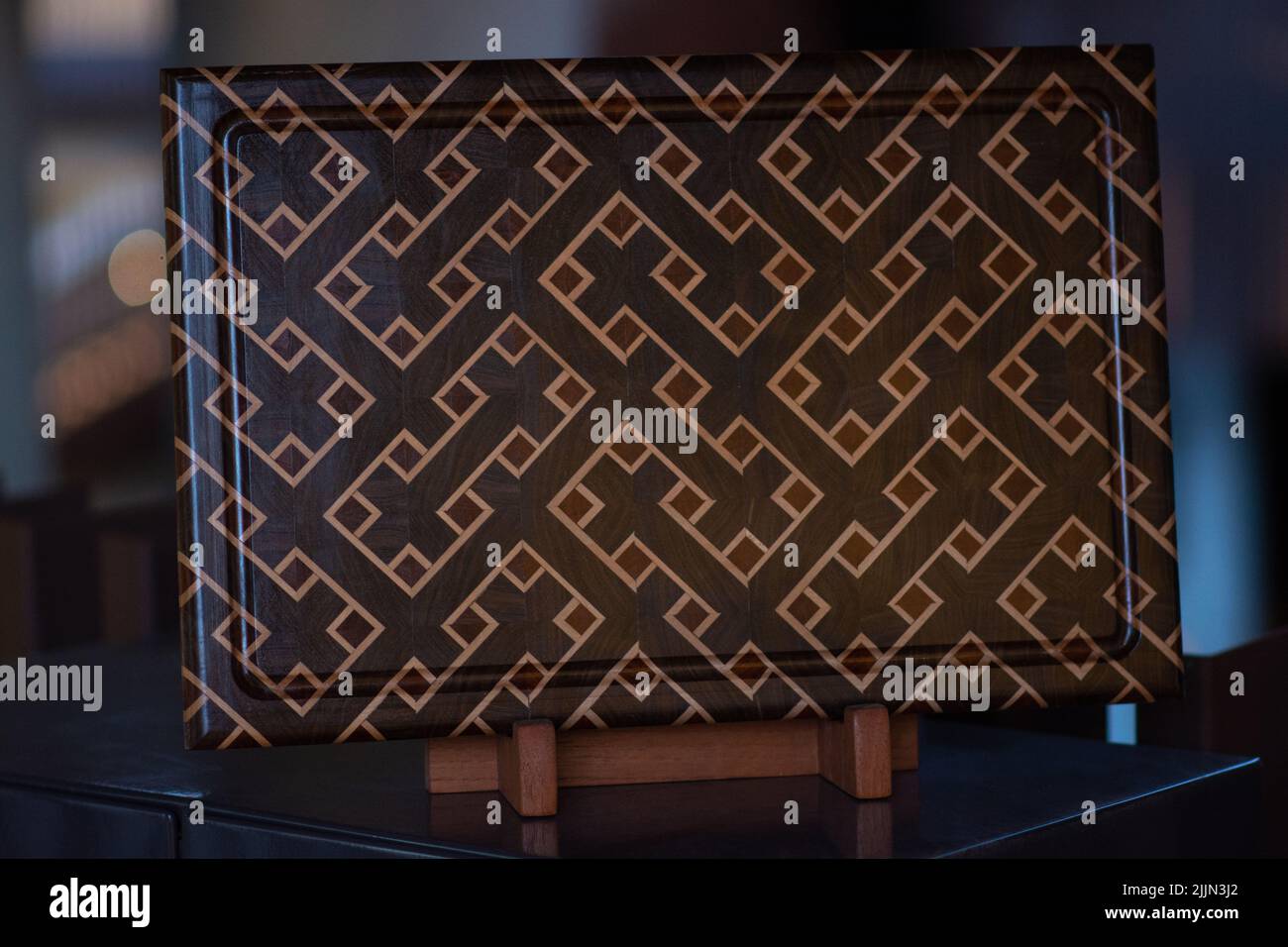 Une planche à découper en bois de fin de grain fabriquée à la main en noyer, érable et acajou sur un support Banque D'Images