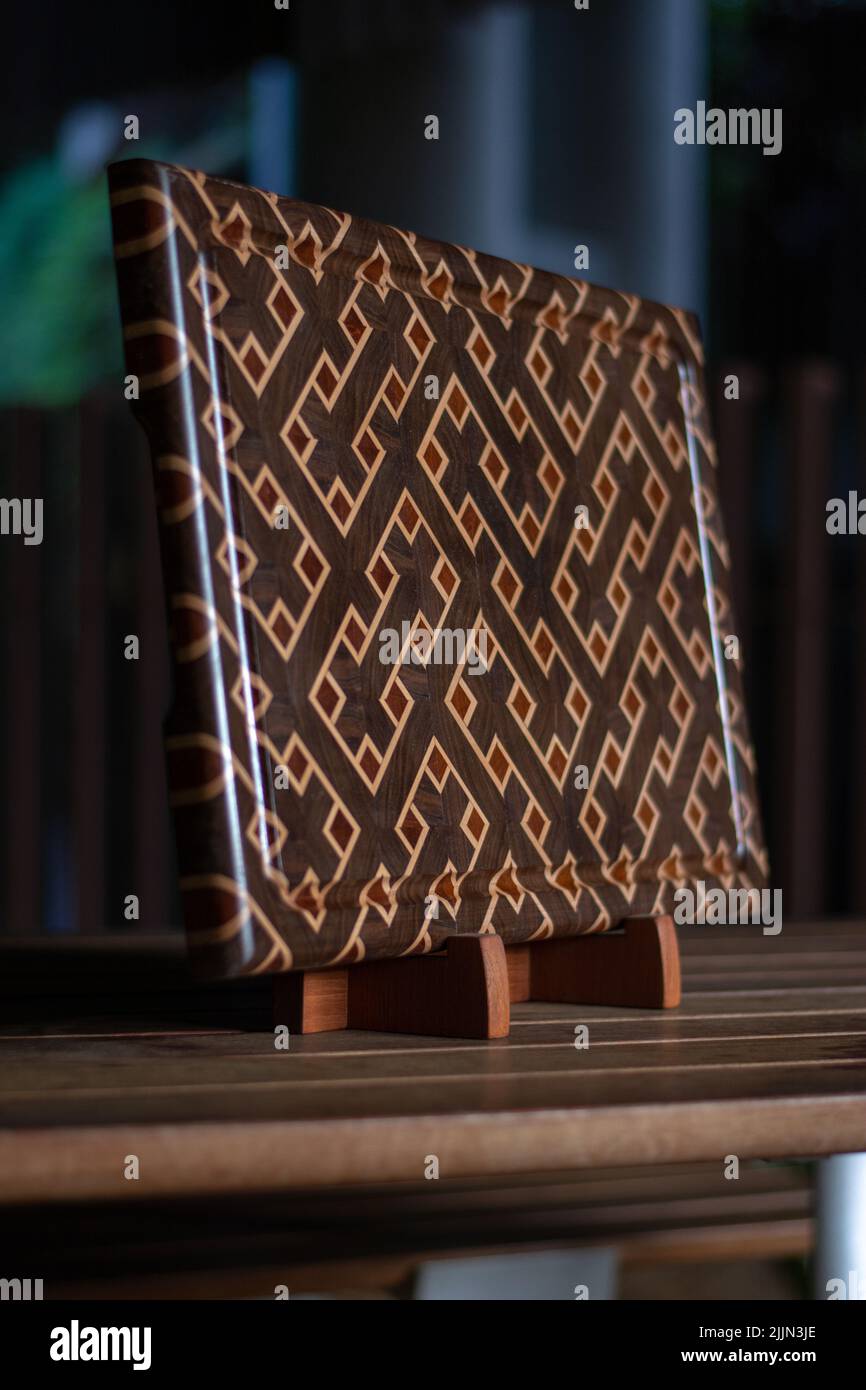 Photo verticale d'une planche à découper en bois à grain fin fabriquée à la main en noyer, érable et acajou Banque D'Images