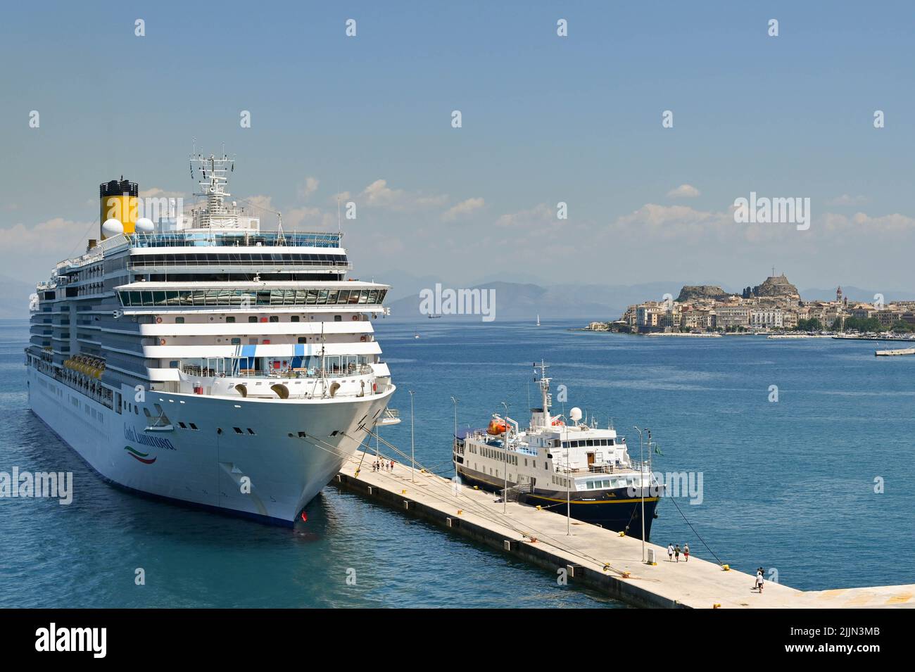 Corfou, Grèce - juin 2022 : bateau de croisière Costa Luminosa et ferry pour petits passagers amarrés dans la ville de Corfou avec la ville et le port en arrière-plan Banque D'Images