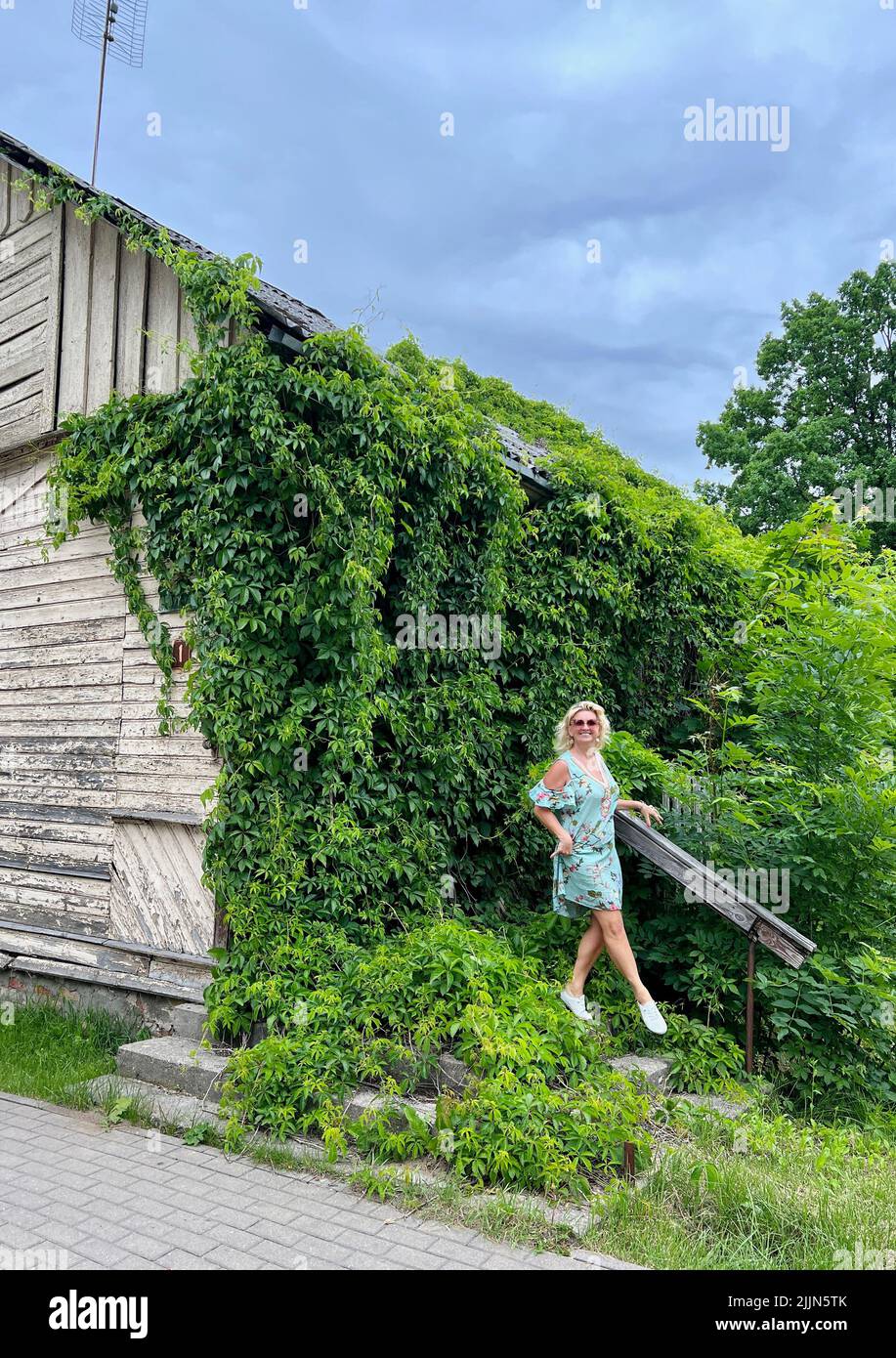 Femme souriante debout près d'une ancienne maison abandonnée, Varena, Lituanie Banque D'Images