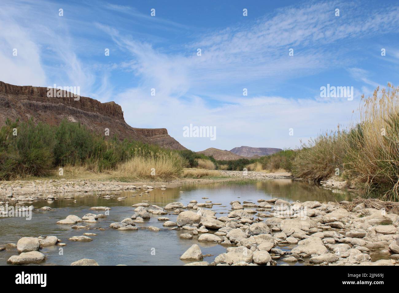 Nuages et falaises de Cirrus en arrière-plan avec la rivière Rio Grande et des rochers au parc national de Big Bend Ranch au Texas Banque D'Images