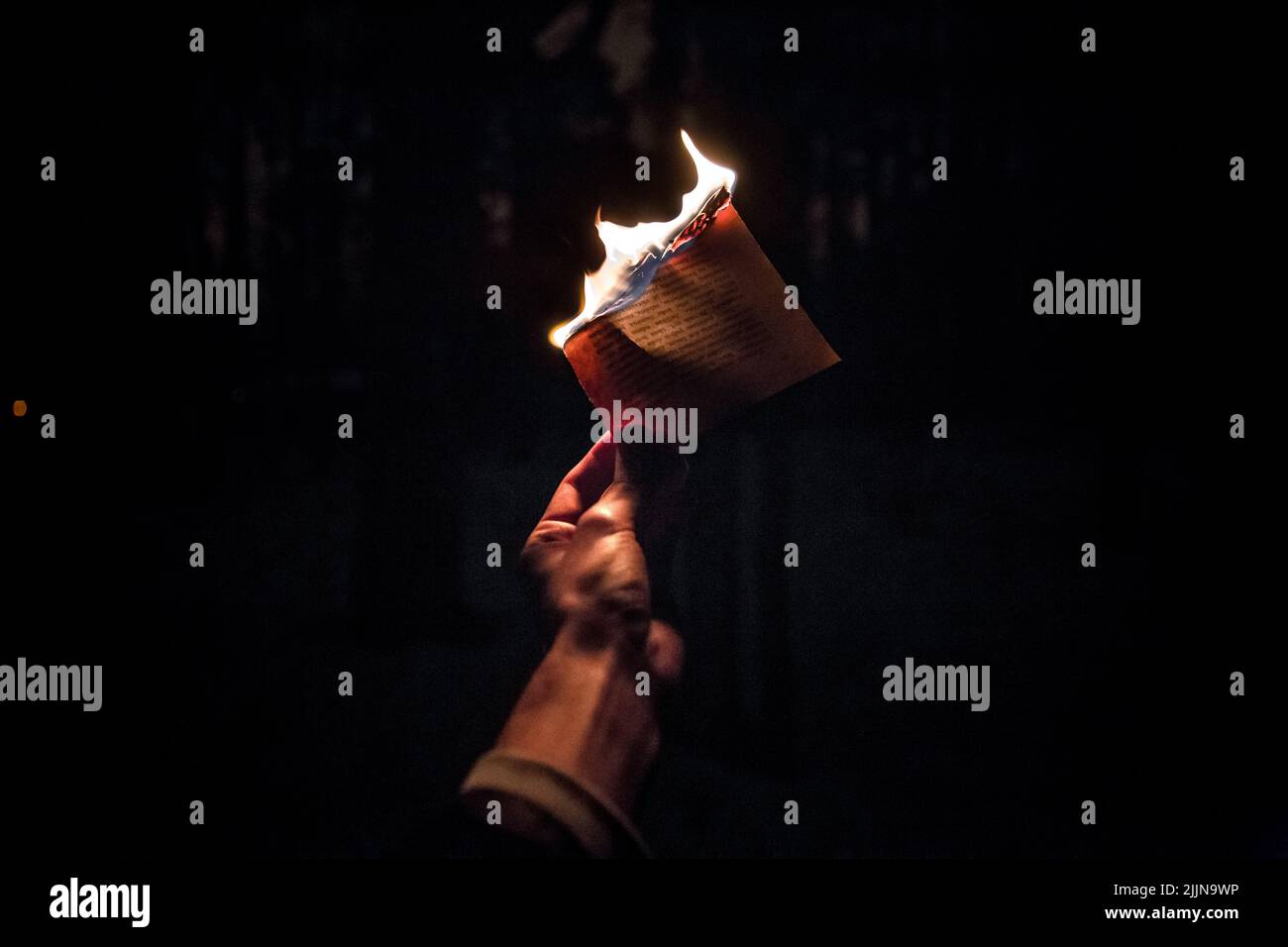 Gros plan d'une personne tenant un papier en feu Banque D'Images