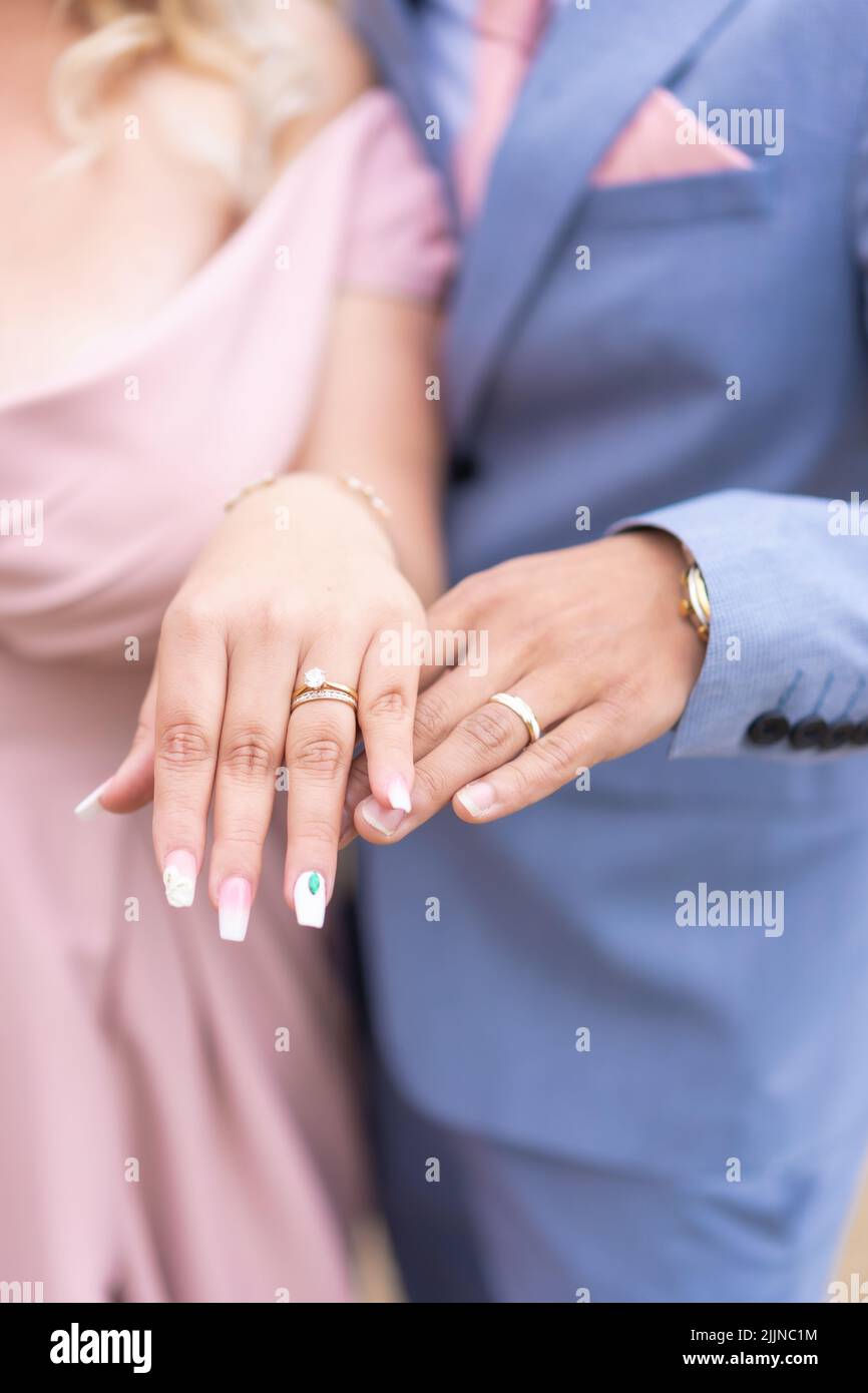 Un gros plan vertical des mains de la jeune mariée et du marié avec les anneaux. Banque D'Images