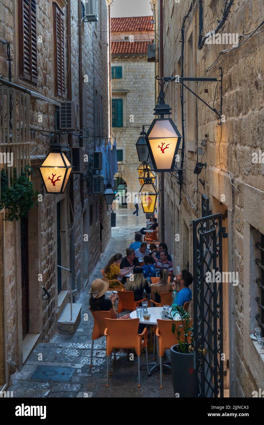 Une photo verticale d'un restaurant en plein air avec des personnes assises à la table dans la rue de la vieille ville, Dubrovnik, Croatie Banque D'Images
