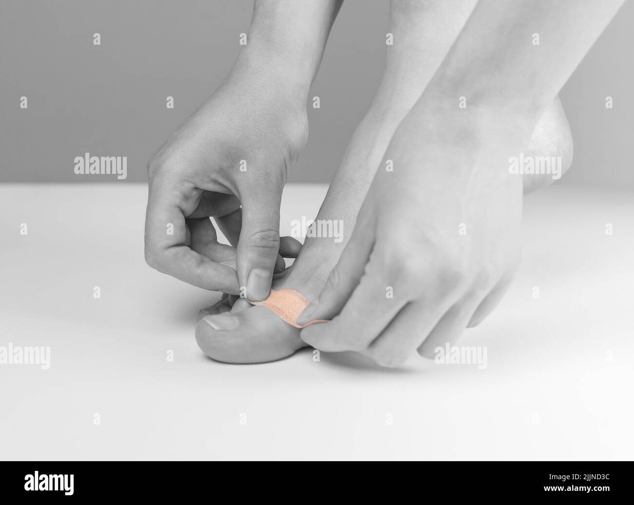 Femme appliquant du plâtre médical sur l'orteil. Premiers soins, concept de médecine. Coupures, abrasions et plaies légèrement saignantes, cicatrisation des cornes. Noir et blanc. Photo de haute qualité Banque D'Images