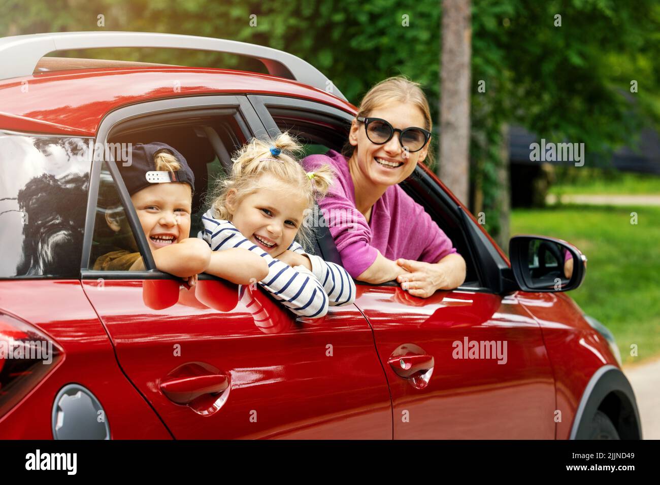 voyage en famille. mère avec des enfants souriant et s'inclinant hors de la fenêtre de la voiture Banque D'Images