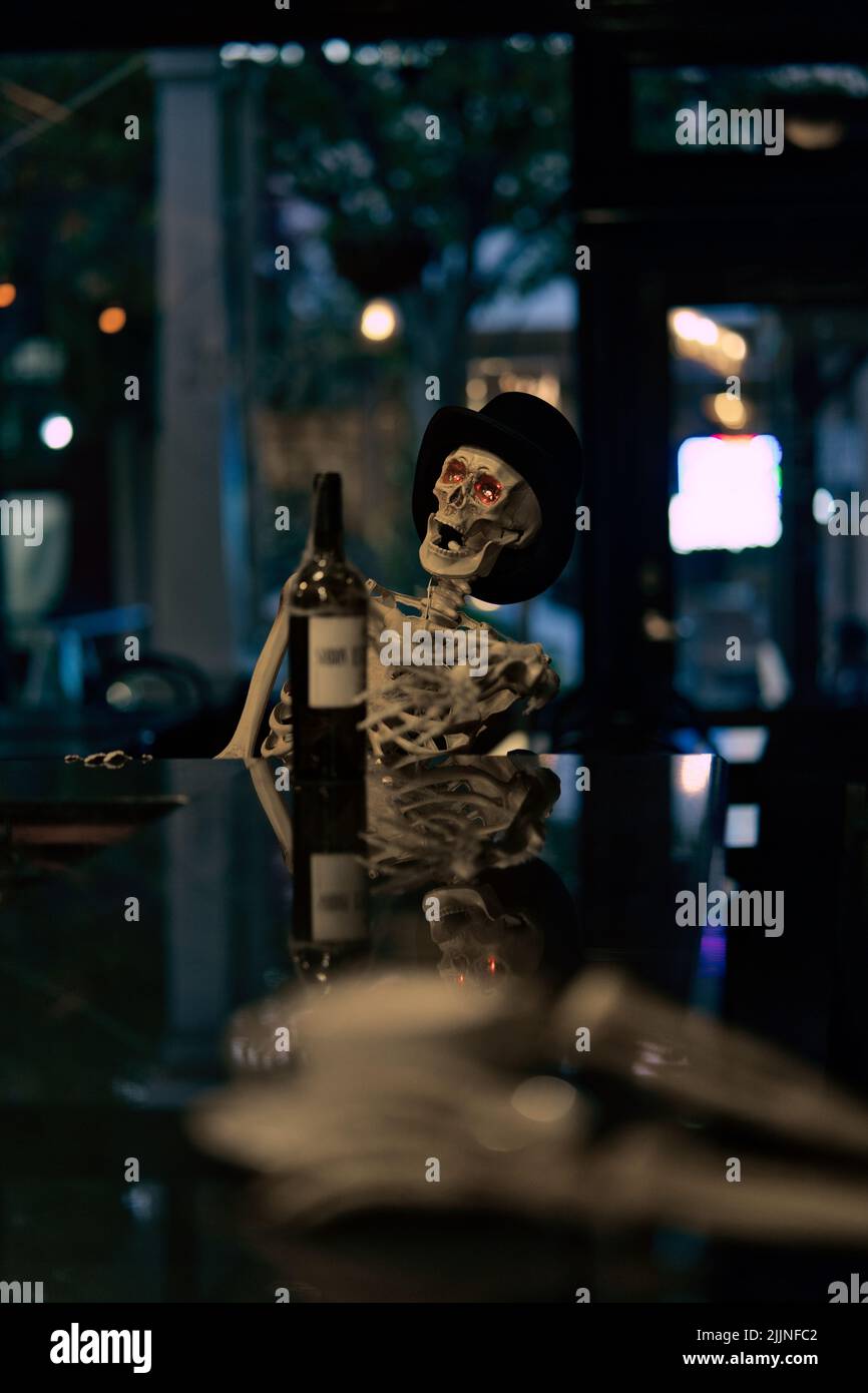 Une photo verticale d'un squelette buvant du vin au bar Banque D'Images