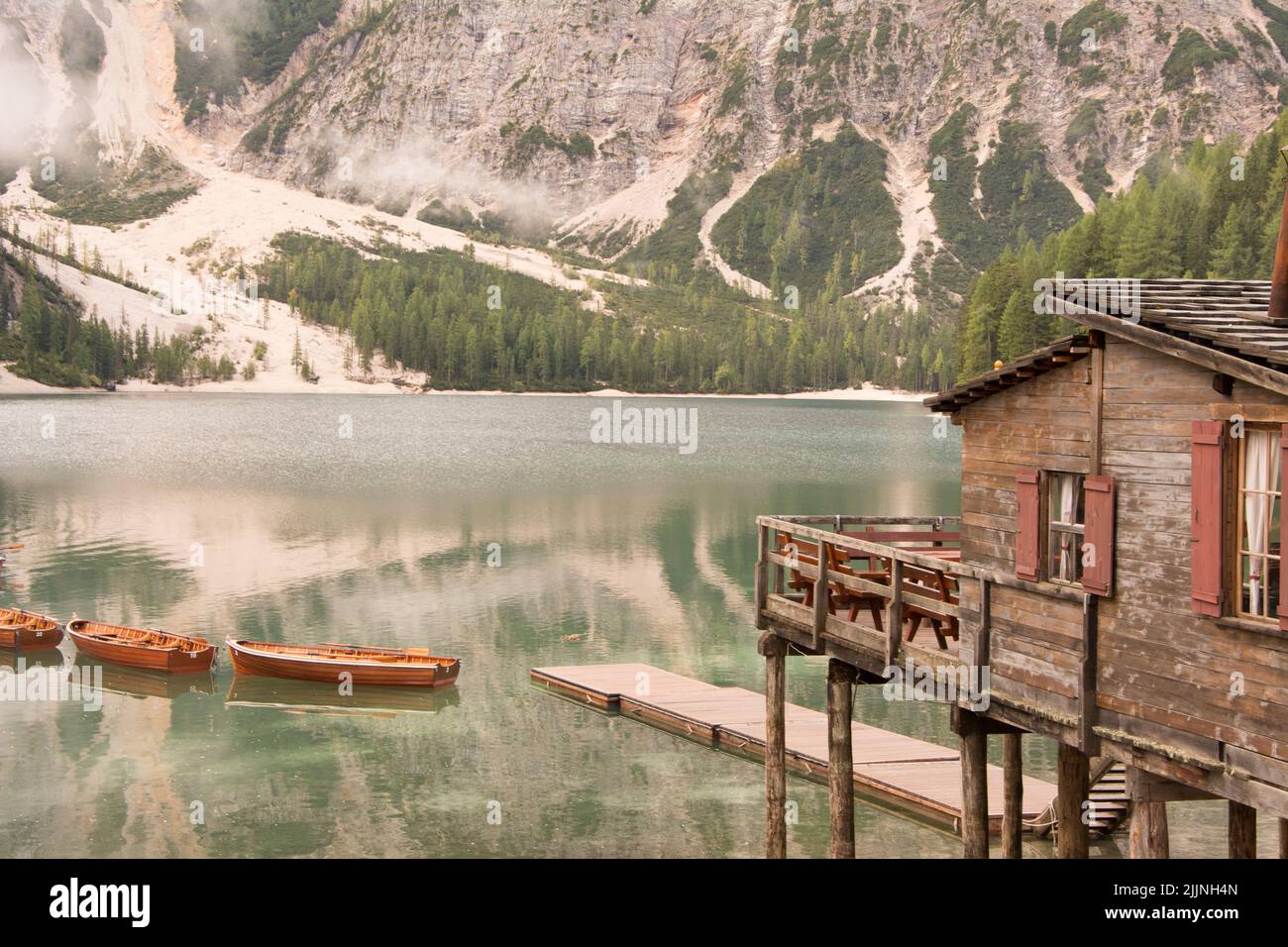 Une belle vue sur une ancienne cabine en bois avec des bateaux dans un lac et des montagnes en arrière-plan Banque D'Images