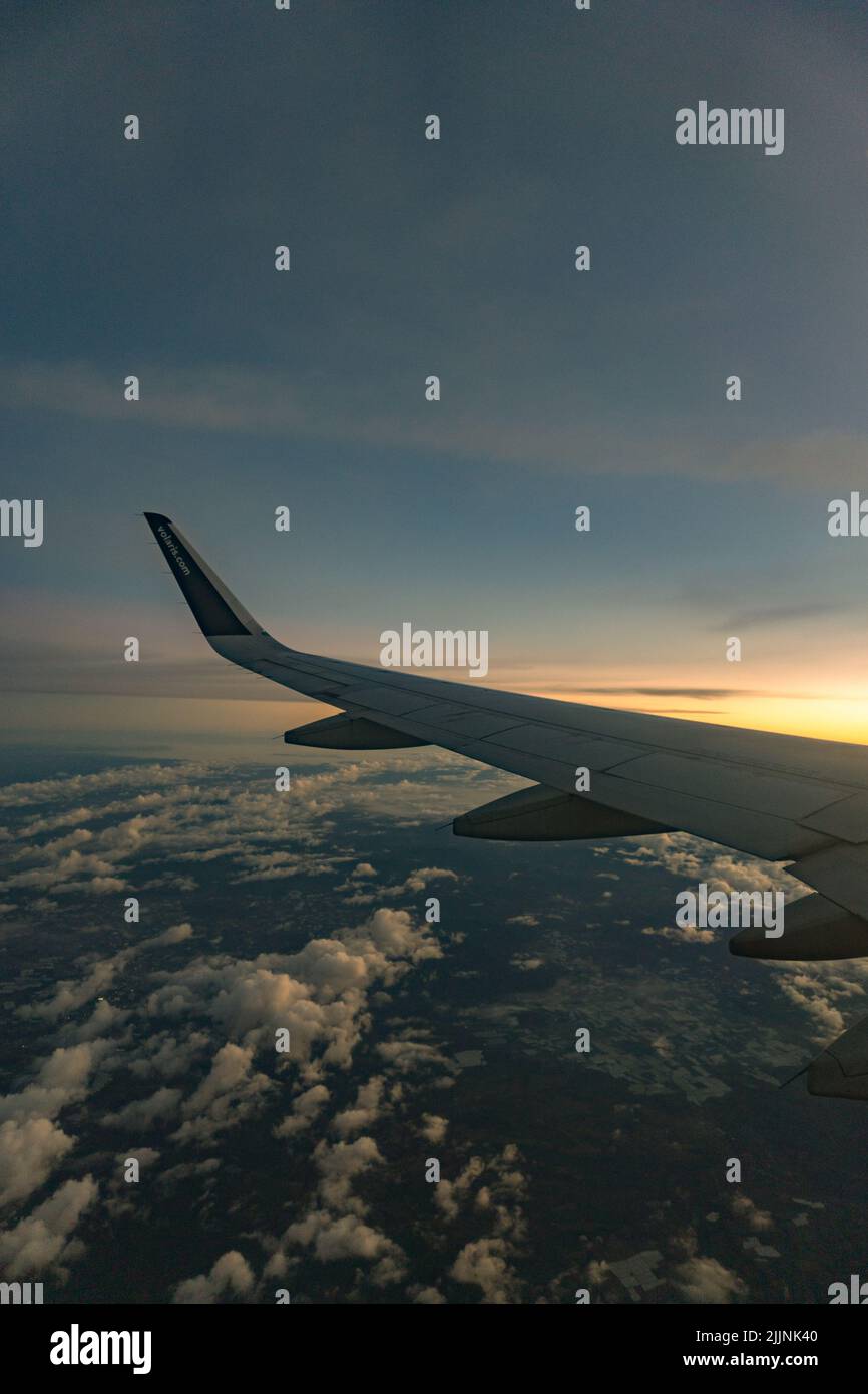 Une vue aérienne depuis l'avion, l'aile de l'avion au coucher du soleil depuis le côté droit au-dessus de l'horizon des nuages Banque D'Images