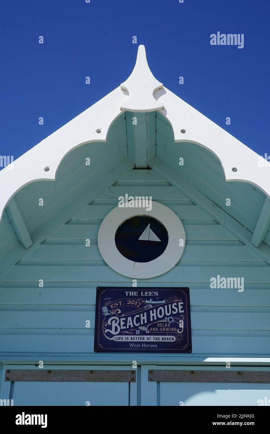 La photo montre une rangée de cabanes de plage aux couleurs vives bordant une plage de sable, et sont peintes dans une variété de couleurs, y compris le rouge, le bleu, le jaune. Banque D'Images