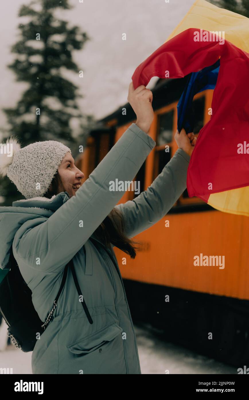 Une photo verticale d'une femme caucasienne portant le drapeau moldave à côté d'un train jaune Banque D'Images