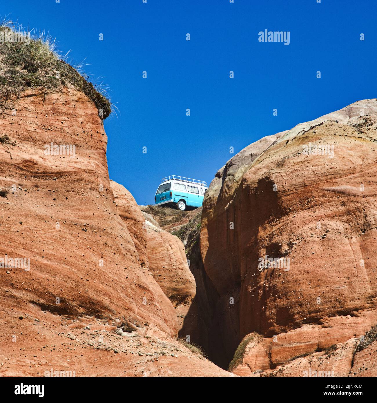 Une voiture de camping garée au sommet d'une falaise contre un ciel bleu Banque D'Images