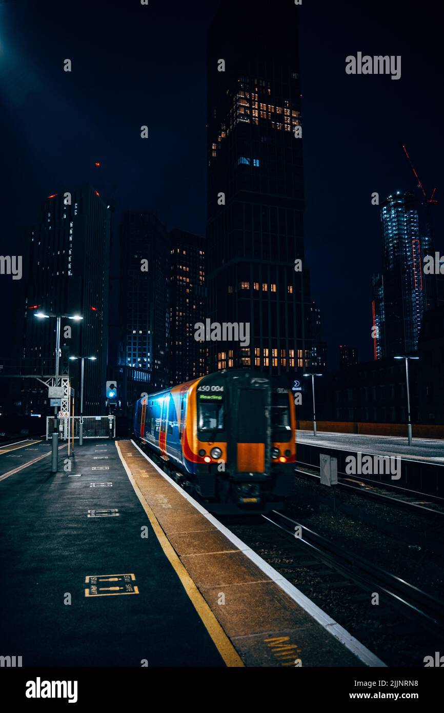 Un cliché vertical d'un train arrivant à la gare la nuit Banque D'Images