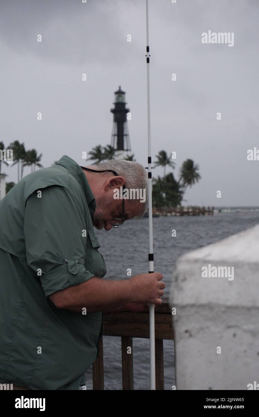 Une photo verticale d'un pêcheur fixant sa tige lors d'une journée sombre à l'extérieur Banque D'Images