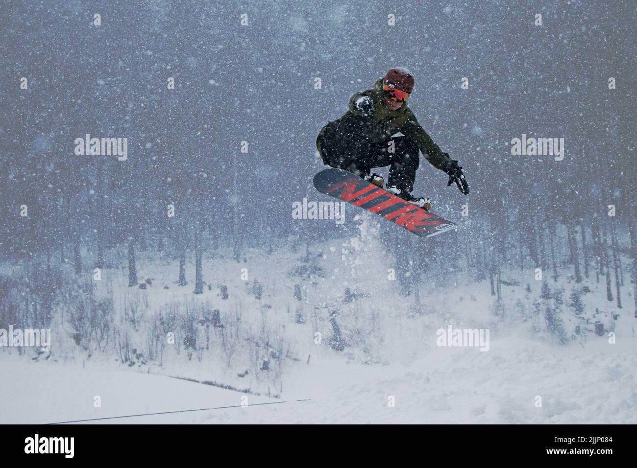 Un Snowboarder faire un saut dans une tempête de neige dans les montagnes suisses Banque D'Images